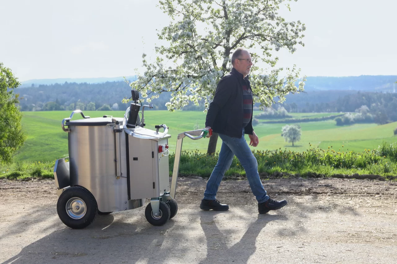 Ein Landwirt zieht das MilchMobil durch eine natürliche Umgebung, umgeben von grüner Landschaft